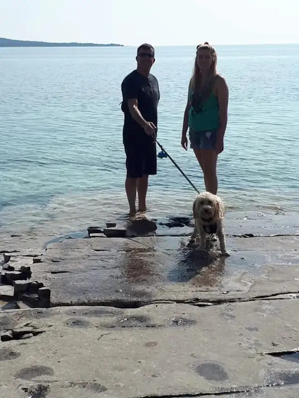 two people standing at a lake with a dog