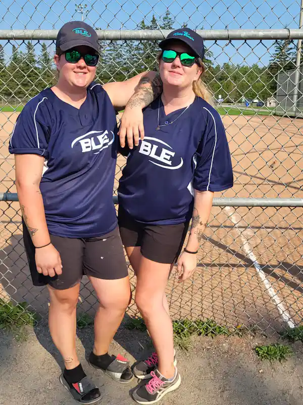 two girls wearing baseball outfits