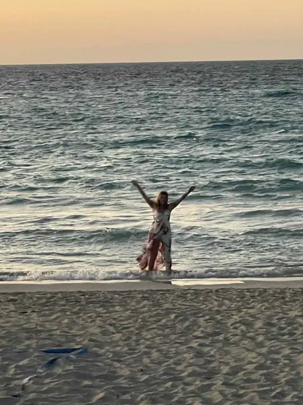 girl waving from the shoreline