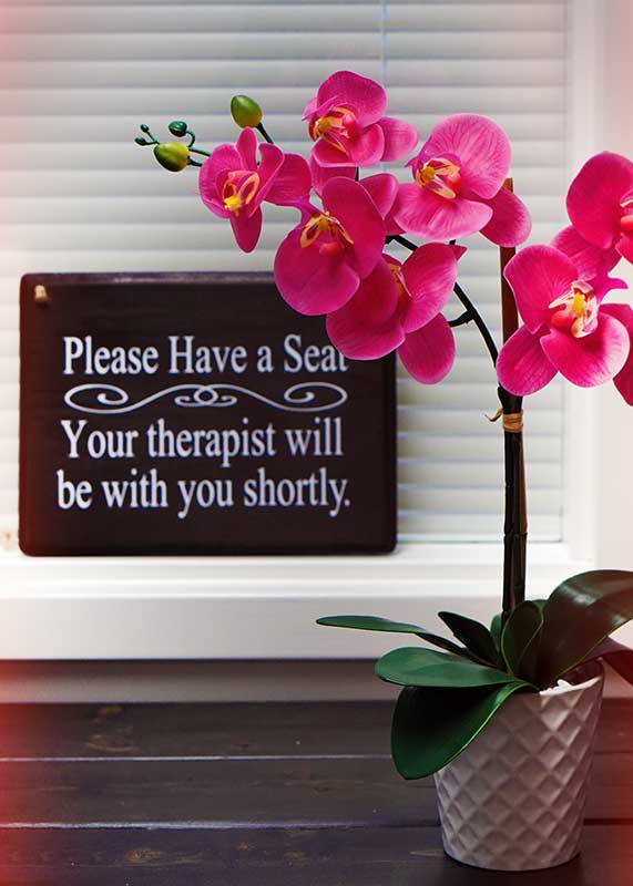 Please have a seat sign by a pink flowering plant