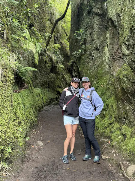 two people are standing in a canyon on a hiking trail