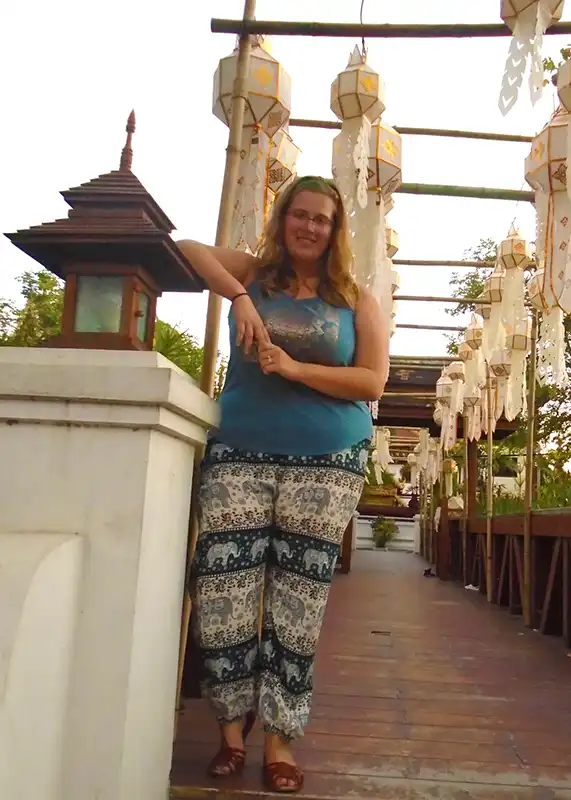 lantern-festival A person stands on a decorated wooden walkway, adorned with lanterns and traditional designs, under a partially cloudy sky.